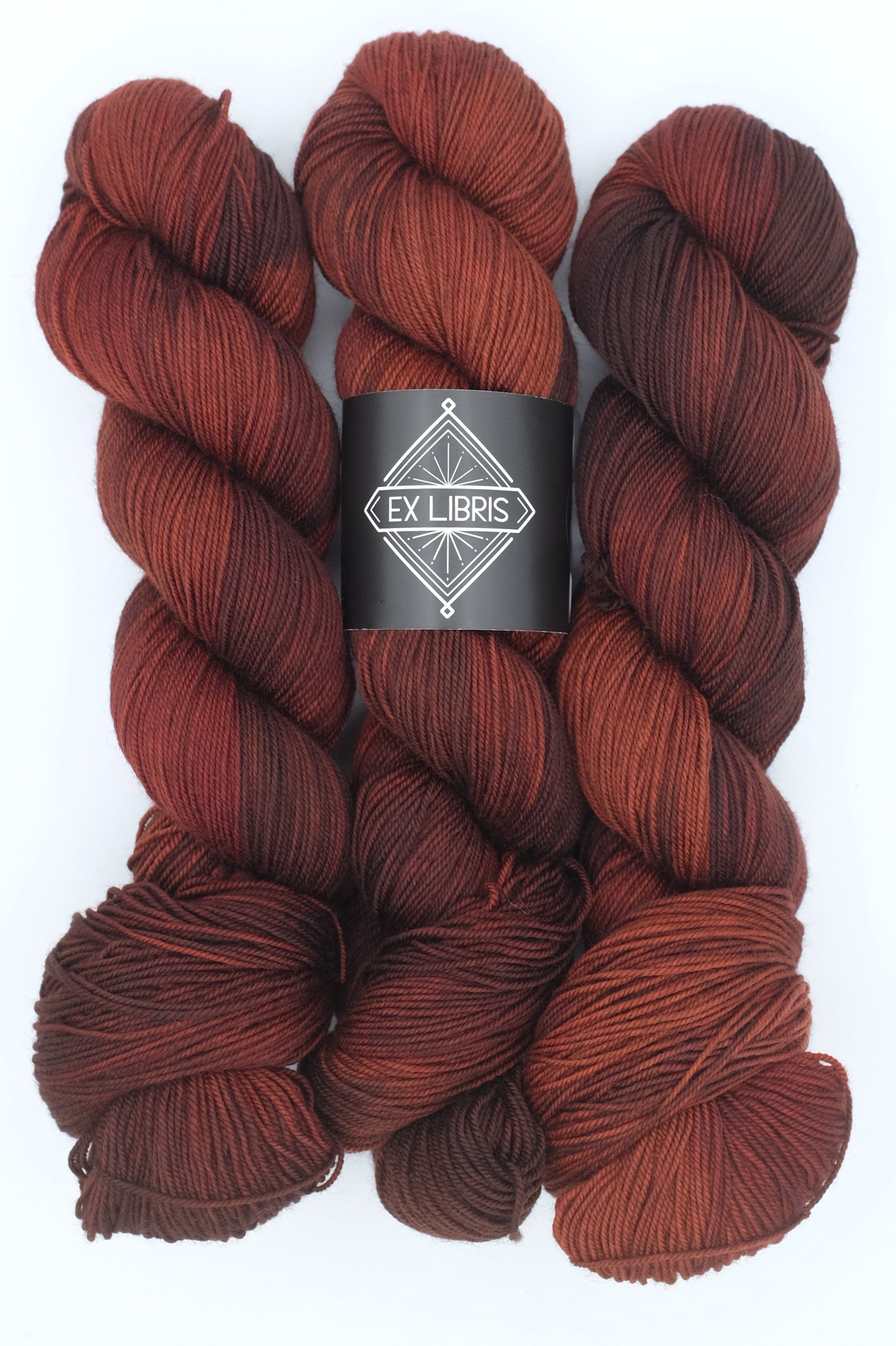 Three skeins of red yarn with a 'Ex Libris' label on a white background