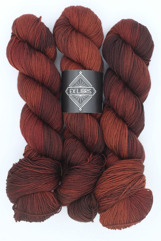 Three skeins of red yarn with a 'Ex Libris' label on a white background