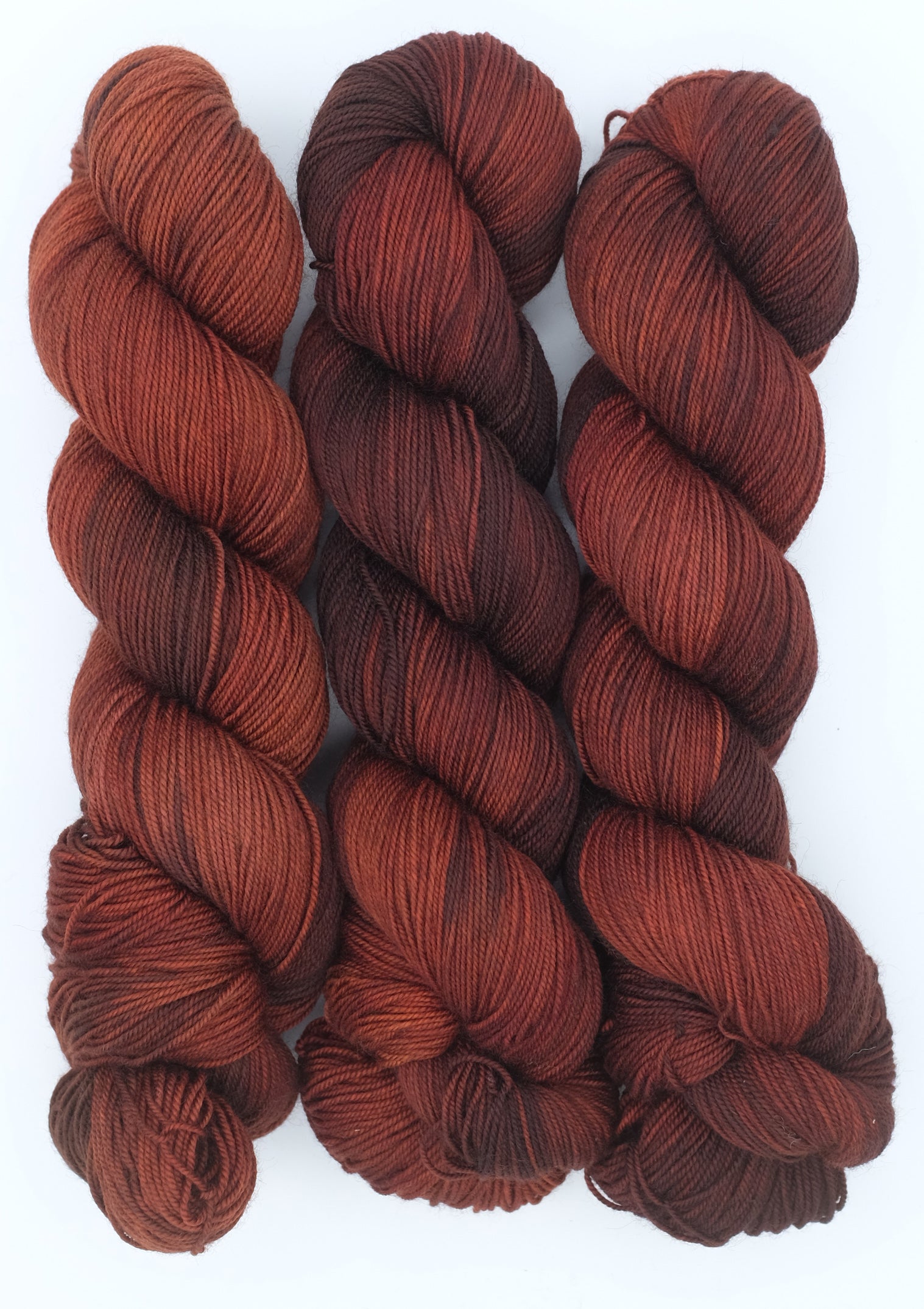Three skeins of red-brown yarn on a white background